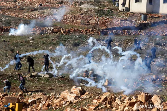 Palestinians try to avoid tear gas fired by Israeli soldiers during clashes which erupted after the funeral of Palestinian Mustafa Tamimi in the West Bank town of Nabi Saleh, Sunday, Dec. 11, 2011. Tamimi, 28, was hurlin...