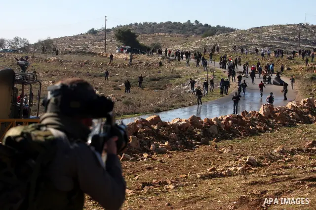 An Israeli soldier fires tear gas towards Palestinian demonstrators during clashes which erupted after the funeral of Palestinian Mustafa Tamimi in the West Bank town of Nabi Saleh, Sunday, Dec. 11, 2011. Tamimi, 28, was...