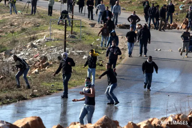 Palestinian youths throw stones at Israeli soldiers during clashes which erupted after the funeral of Palestinian Mustafa Tamimi in the West Bank town of Nabi Saleh, Sunday, Dec. 11, 2011. Tamimi, 28, was hurling rocks a...