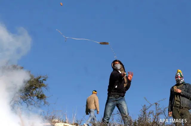 Palestinian youths throw stones at Israeli soldiers during clashes which erupted after the funeral of Palestinian Mustafa Tamimi in the West Bank town of Nabi Saleh, Sunday, Dec. 11, 2011. Tamimi, 28, was hurling rocks a...