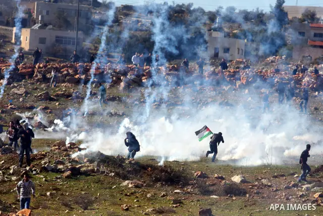 Palestinians try to avoid tear gas fired by Israeli soldiers during clashes which erupted after the funeral of Palestinian Mustafa Tamimi in the West Bank town of Nabi Saleh, Sunday, Dec. 11, 2011. Tamimi, 28, was hurlin...