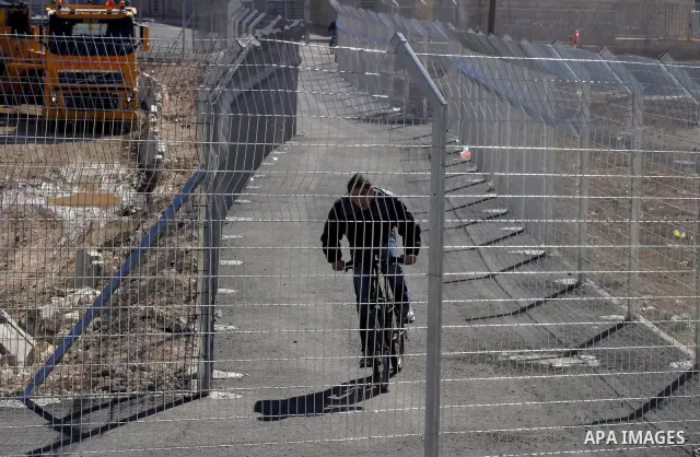 Israeli soldiers stand guard as Palestinians cross through the new opened Israeli checkpoint near the east Jerusalem refugee camp of Shuafat on December 12, 2011. Palestinian youths protested against the construction of...