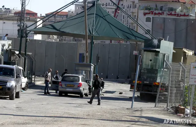 Israeli soldiers stand guard as Palestinians cross through the new opened Israeli checkpoint near the east Jerusalem refugee camp of Shuafat on December 12, 2011. Palestinian youths protested against the construction of...