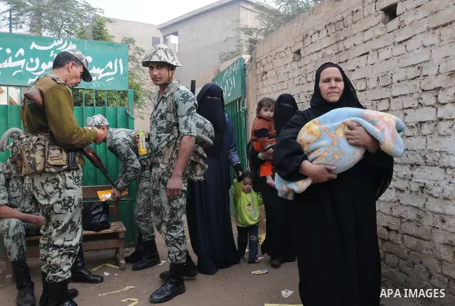 Egyptian women wait to vote outside a polling station in Giza, southwest of Cairo, on December 14, 2011, during the second stage of Egypt's parliamentary elections. Some 18.8 million Egyptians are eligible to cast their...