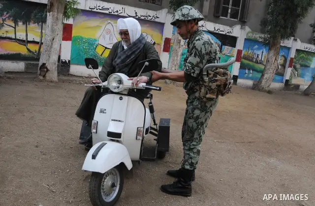 A soldier try to help man waiting to vote into a line in front of a school used as a polling centre during parliamentary elections, in Suez December 14, 2011. Egyptians voted on Wednesday in the second round of a parliam...
