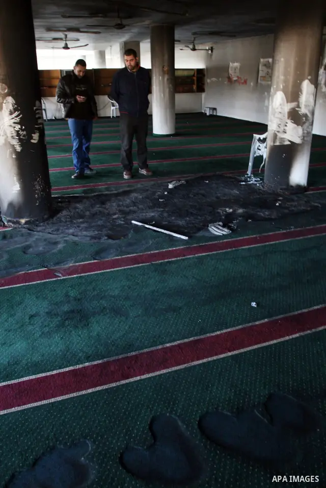 Palestinians from the West bank village of Burqa near Ramallah, view the damage at the village Al-Nur mosque, on 15 December 2011. The mosque was set on fire during the night allegedly by Israeli settlers and Hebrew slog...