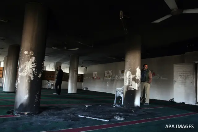 Palestinians from the West bank village of Burqa near Ramallah, view the damage at the village Al-Nur mosque, on 15 December 2011. The mosque was set on fire during the night allegedly by Israeli settlers and Hebrew slog...