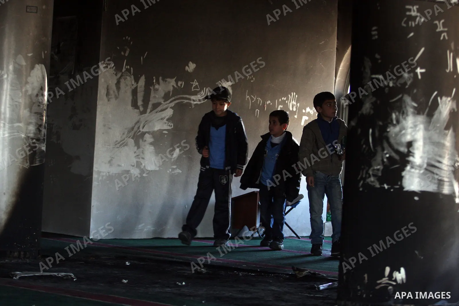 Palestinians from the West bank village of Burqa near Ramallah, view the damage at the village Al-Nur mosque, on 15 December 2011. The mosque was set on fire during the night allegedly by Israeli settlers and Hebrew slog...