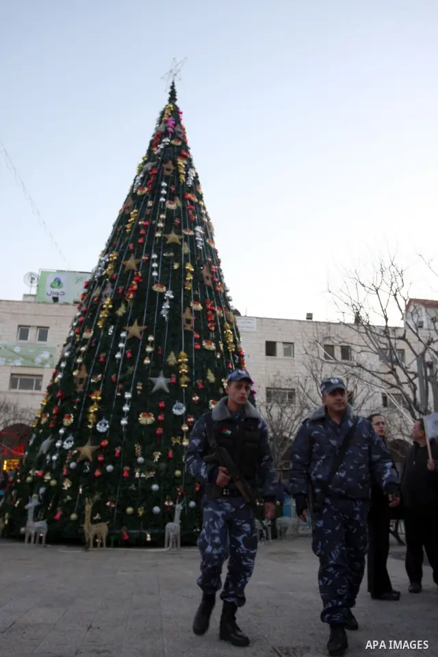 Palestinians watch the lighting of a Christmas tree at Manger Square, outside the Church of the Nativity in West Bank town of Bethlehem,Thursday, Dec. 15, 2011. Christian worshippers began their spiritual preparations ah...