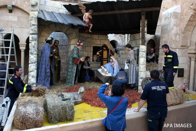 Palestinians watch the lighting of a Christmas tree at Manger Square, outside the Church of the Nativity in West Bank town of Bethlehem,Thursday, Dec. 15, 2011. Christian worshippers began their spiritual preparations ah...