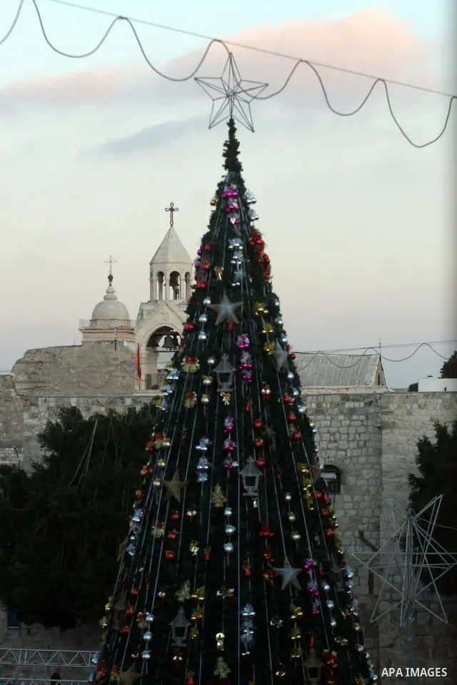 Palestinians watch the lighting of a Christmas tree at Manger Square, outside the Church of the Nativity in West Bank town of Bethlehem,Thursday, Dec. 15, 2011. Christian worshippers began their spiritual preparations ah...