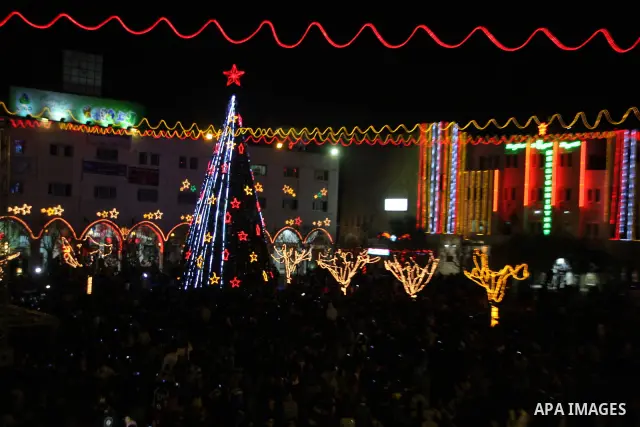 Palestinians watch the lighting of a Christmas tree at Manger Square, outside the Church of the Nativity in West Bank town of Bethlehem,Thursday, Dec. 15, 2011. Christian worshippers began their spiritual preparations ah...