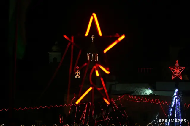 Palestinians watch the lighting of a Christmas tree at Manger Square, outside the Church of the Nativity in West Bank town of Bethlehem,Thursday, Dec. 15, 2011. Christian worshippers began their spiritual preparations ah...