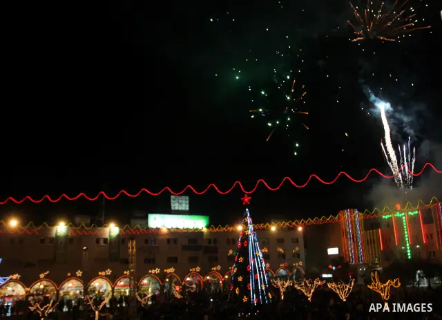 Palestinians watch the lighting of a Christmas tree at Manger Square, outside the Church of the Nativity in West Bank town of Bethlehem,Thursday, Dec. 15, 2011. Christian worshippers began their spiritual preparations ah...