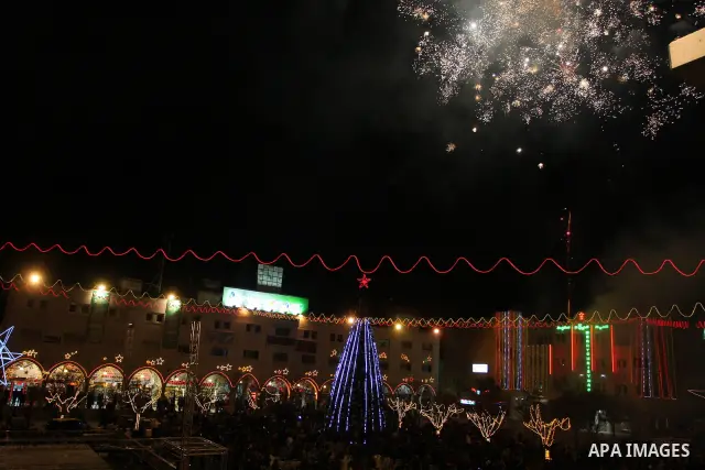 Palestinians watch the lighting of a Christmas tree at Manger Square, outside the Church of the Nativity in West Bank town of Bethlehem,Thursday, Dec. 15, 2011. Christian worshippers began their spiritual preparations ah...