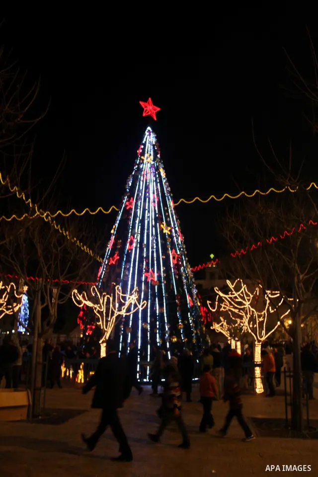 Palestinians watch the lighting of a Christmas tree at Manger Square, outside the Church of the Nativity in West Bank town of Bethlehem,Thursday, Dec. 15, 2011. Christian worshippers began their spiritual preparations ah...