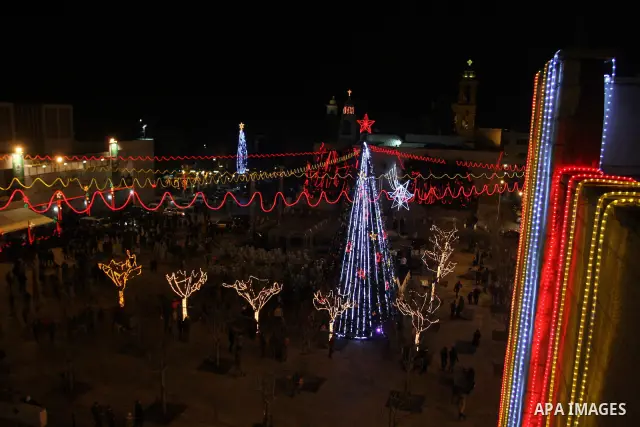 Palestinians watch the lighting of a Christmas tree at Manger Square, outside the Church of the Nativity in West Bank town of Bethlehem,Thursday, Dec. 15, 2011. Christian worshippers began their spiritual preparations ah...