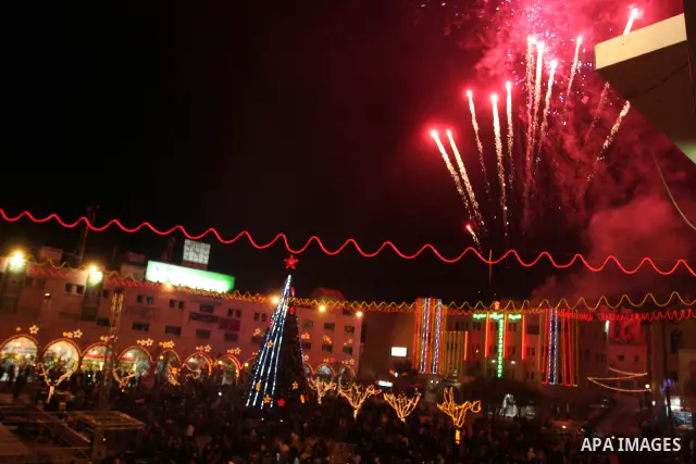 Palestinians watch the lighting of a Christmas tree at Manger Square, outside the Church of the Nativity in West Bank town of Bethlehem,Thursday, Dec. 15, 2011. Christian worshippers began their spiritual preparations ah...
