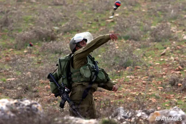 An Israeli soldier hurls tear gas canister towards Palestinian demonstrators during clashes at a weekly protest against a nearby Jewish settlement, in the West Bank village of Nabi Saleh, near Ramallah December 16, 2011....
