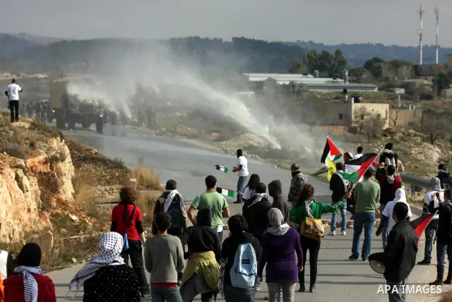Palestinian and left-wing Israeli demonstrators run from a tear gas grenade fired by Israeli security officers during clashes at a weekly protest against a nearby Jewish settlement, in the West Bank village of Nabi Saleh...