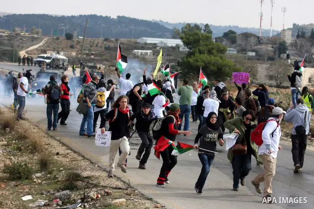 Palestinian and left-wing Israeli demonstrators run from a tear gas grenade fired by Israeli security officers during clashes at a weekly protest against a nearby Jewish settlement, in the West Bank village of Nabi Saleh...