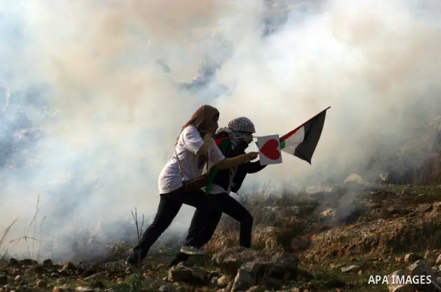 Palestinian and left-wing Israeli demonstrators run from a tear gas grenade fired by Israeli security officers during clashes at a weekly protest against a nearby Jewish settlement, in the West Bank village of Nabi Saleh...