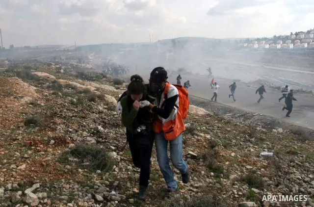 Palestinian and left-wing Israeli demonstrators run from a tear gas grenade fired by Israeli security officers during clashes at a weekly protest against a nearby Jewish settlement, in the West Bank village of Nabi Saleh...