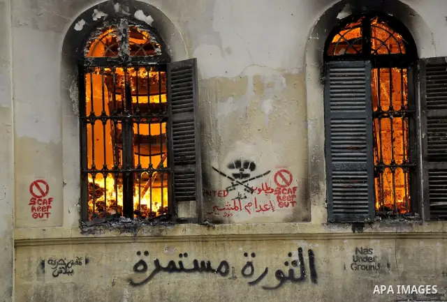 Egyptian demonstrators throw stones towards security forces in front of a building in fire, in Kasr al-Aini Cairo, Egypt, 17 December 2011. Accoring to media reports, The clashes, the worst in three weeks, erupted on 16...