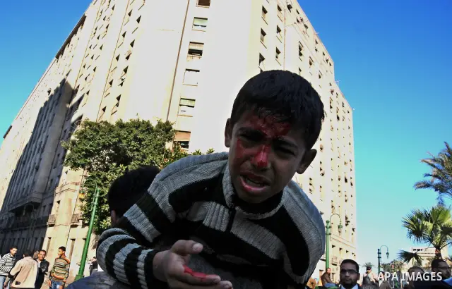 Egyptian medics help a young protester near Tahrir Square in Cairo, Egypt, Sunday, Dec. 18, 2011. Troops and protesters are clashing for the third straight day in Cairo, pelting each other with rocks in skirmishes near p...