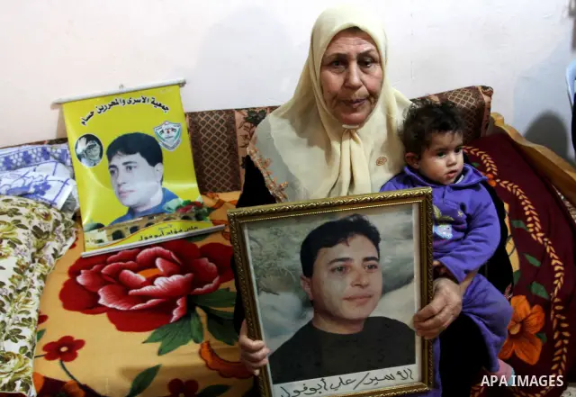 The mother of Palestinian prisoner Ali Abu Fool holds his picture before his release from an Israeli jail, in Gaza City December 18, 2011. Israel plans to release 550 Palestinian prisoners on Sunday in the second stage o...