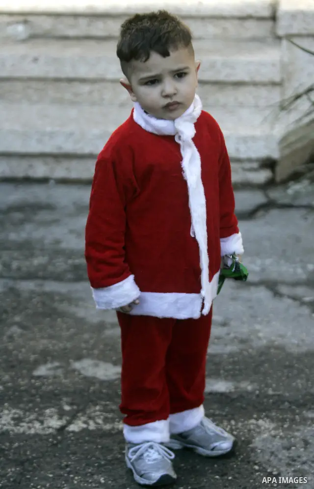 A Palestinian boy dressed as Santa Claus attends a celebration ahead of Christmas at Deir al-Laten Church in Gaza City December 18, 2011. Photo by Yasser Fathi