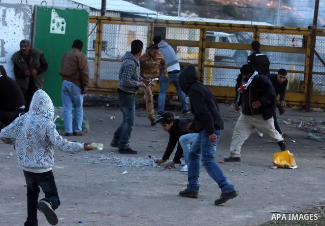 Palestinian youths throw stones towards Israeli soldiers during clashes outside Ofer prison, near the West Bank city of Ramallah December 18, 2011. The clashes erupted while Palestinians gathered to wait for the release...
