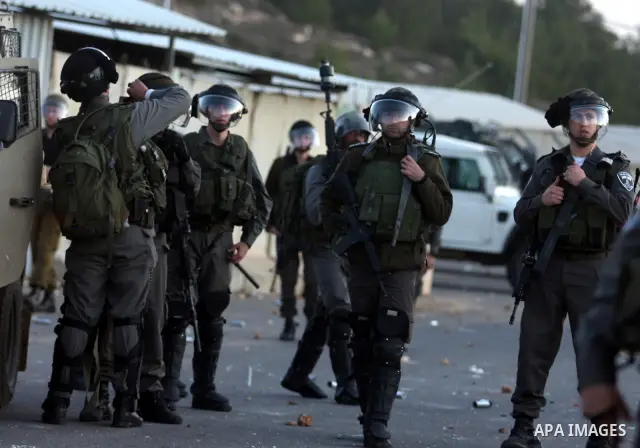 Israeli border police officers stand in front Palestinian stone-throwers during clashes outside Ofer prison, near the West Bank city of Ramallah December 18, 2011. The clashes erupted while Palestinians gathered to wait...