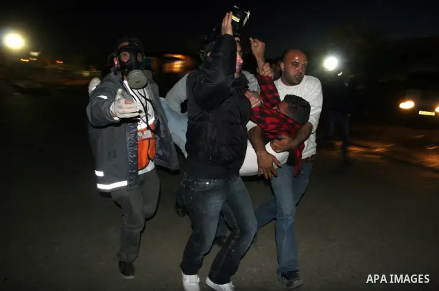 Palestinian medics help a wounded man during clashes with Israeli soldiers outside Ofer prison, near the West Bank city of Ramallah December 18, 2011. The clashes erupted while Palestinians gathered to wait for the relea...