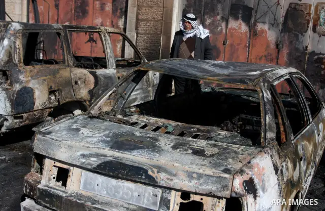 A Palestinian man inspects burnt cars after unidentified assailants torched them in the West Bank village of Beitin, north of Ramallah, on December 19, 2011 in a possible revenge attack by extremist Jews, police said. Ph...