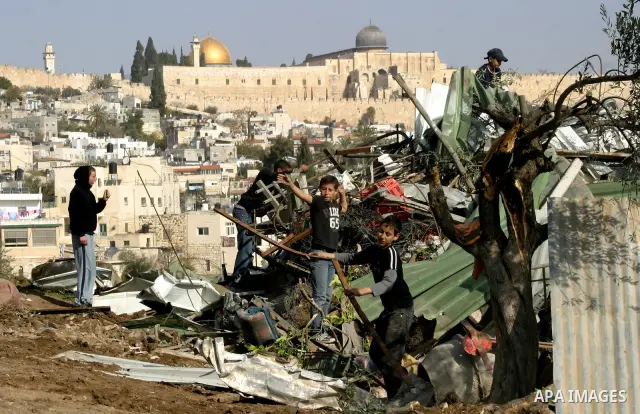 Palestinians sit on the rubble of a storehouse after an Israeli bulldozer destroys a storehouse in east Jerusalem neighborhood of Silwan on Dec 20,2011, where Palestinian houses are threatened to be demolished by the Isr...