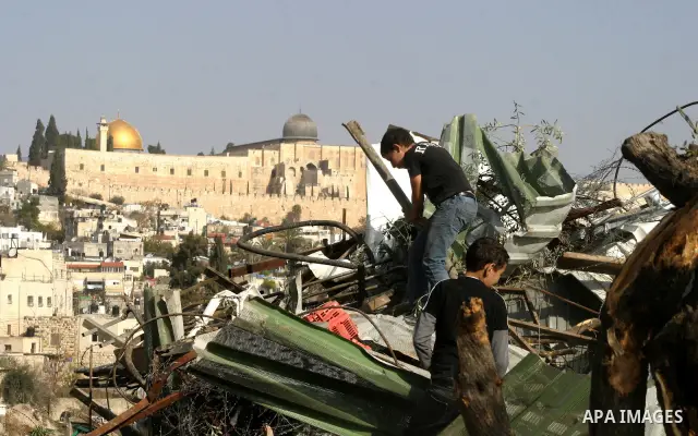 Palestinians sit on the rubble of a storehouse after an Israeli bulldozer destroys a storehouse in east Jerusalem neighborhood of Silwan on Dec 20,2011, where Palestinian houses are threatened to be demolished by the Isr...