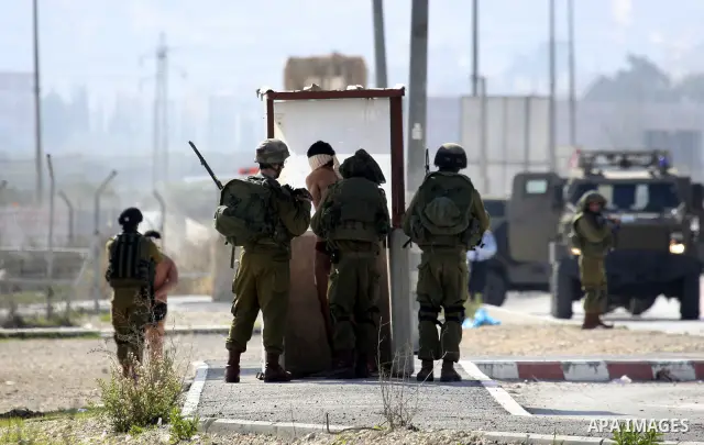Israeli soldiers lead a stripped, blindfolded and handcuffed Palestinain youth to the back of the Huwara checkpoint after they suspected he was carrying explosives along with another boy near the West Bank city of Nablus...