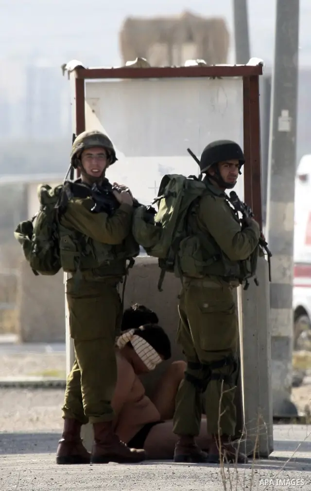 Israeli soldiers lead a stripped, blindfolded and handcuffed Palestinain youth to the back of the Huwara checkpoint after they suspected he was carrying explosives along with another boy near the West Bank city of Nablus...