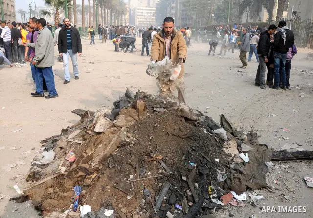 Egyptian protesters gather debris in a street by the Institute of Egypt, which was torched during protests, in central Cairo on December 20, 2011. Clashes between Egyptian security forces and protesters demanding an end...
