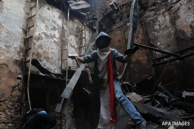 Smokes rises as an Egyptian protester helps extinguish smoldering valuable books and documents salvaged from the two story building of the Egyptian Scientific Complex after it was almost gutted by fire which broke out du...