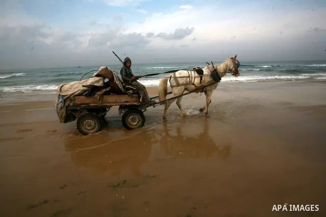 A Palestinian child walks near the sea of Gaza City, trying collects scrap metal. Dec. 21, 2011. Photo by Mahmud Nassar