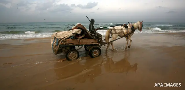 A Palestinian child walks near the sea of Gaza City, trying collects scrap metal. Dec. 21, 2011. Photo by Mahmud Nassar