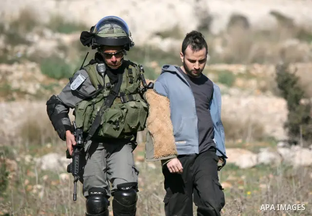 A Palestinian protester is detained by Israeli soldiers during clashes at a weekly protest against a nearby Jewish settlement, in the West Bank village of Nabi Saleh, near Ramallah December 23, 2011. Some 100 demonstrato...