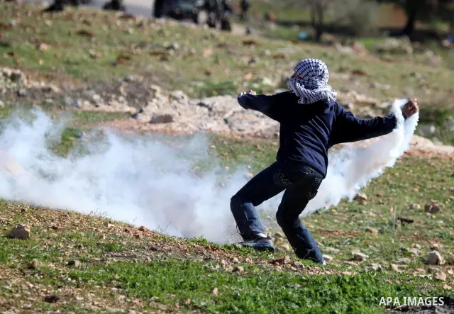 A Palestinian demonstrator hurls tear gas canister towards Israeli security forces during clashes at a weekly protest against a nearby Jewish settlement, in the West Bank village of Nabi Saleh, near Ramallah December 23,...