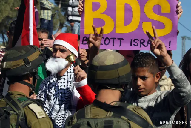 An Israeli soldier pushes back a demonstrator dressed as Santa Claus and holding a Palestinian flag during a protest against the controversial Israeli barrier in the West Bank village of al-Masara near Bethlehem December...