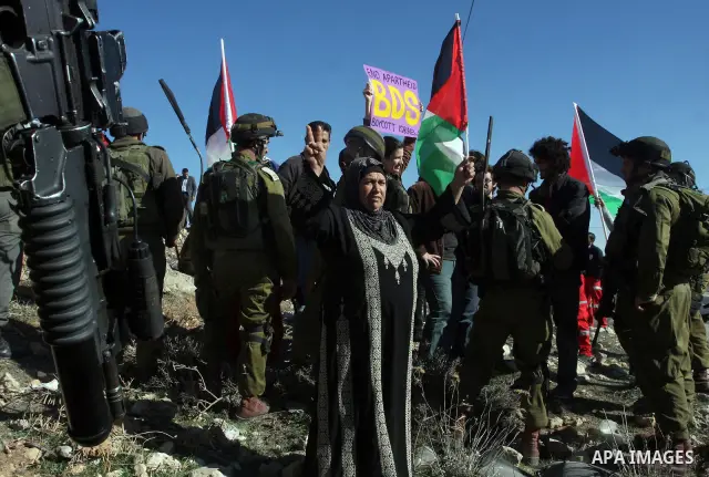 A young demonstrator dressed as Santa Claus stands near Israeli soldiers standing guard during a protest against the controversial Israeli barrier in the West Bank village of al-Masara near Bethlehem December 23, 2011. P...