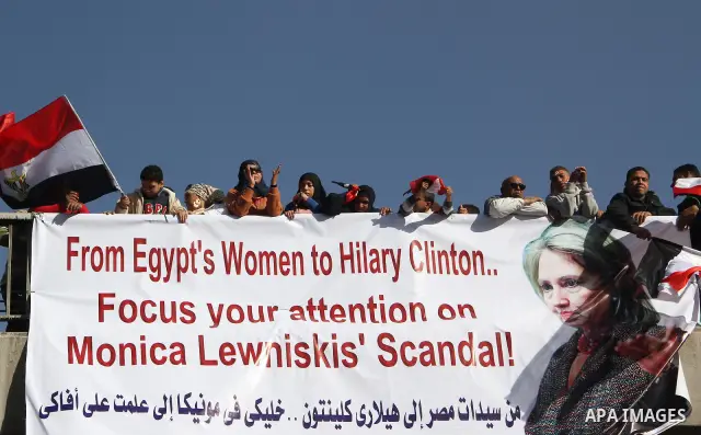 Egyptian pro-military ruling council supporters wave by national flags over a banner with a message to US Secretary of State Hillary Clinton, during their rally to support the council in Cairo, Egypt Friday, Dec. 23, 201...