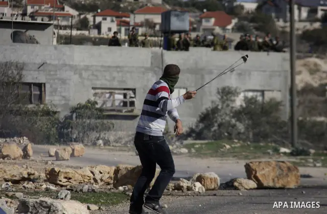 Palestinian youths hurl stones at Israeli security forces ,during a protest in the village of Kufr Qaddum near the Israeli settlement of Kdumim, in the northern West Bank, Friday, Dec. 23, 2011 . Photo by Wagdi Eshtayah.
