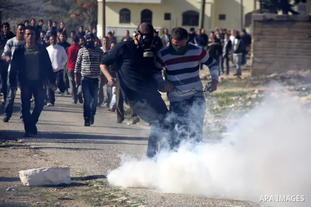 Palestinian protest hurl in tear gas at Israeli security forces ,during a protest in the village of Kufr Qaddum near the Israeli settlement of Kdumim, in the northern West Bank, Friday, Dec. 23, 2011 . Photo by Wagdi Esh...